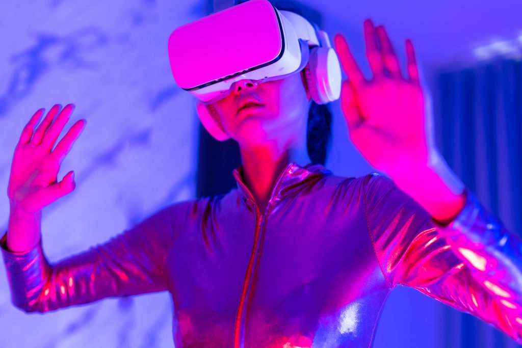 Virtual Reality in Entertainment.Young asian woman is using virtual reality headset. Neon light studio portrait. Concept of virtual reality, simulation, gaming and future technology.Asian woman play game in bedroom.